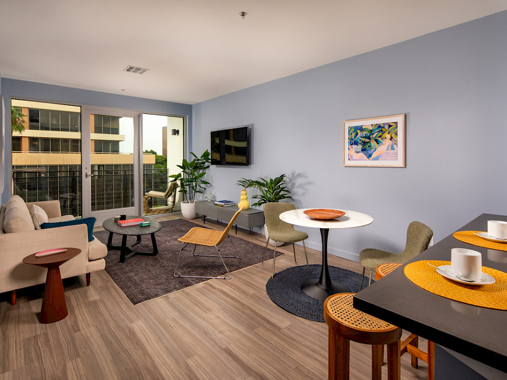 Westlake Apartments - Wilco Apartments Open Living Room with Wood-Style Flooring, Oversized Windows, and Access to Patio/Balcony